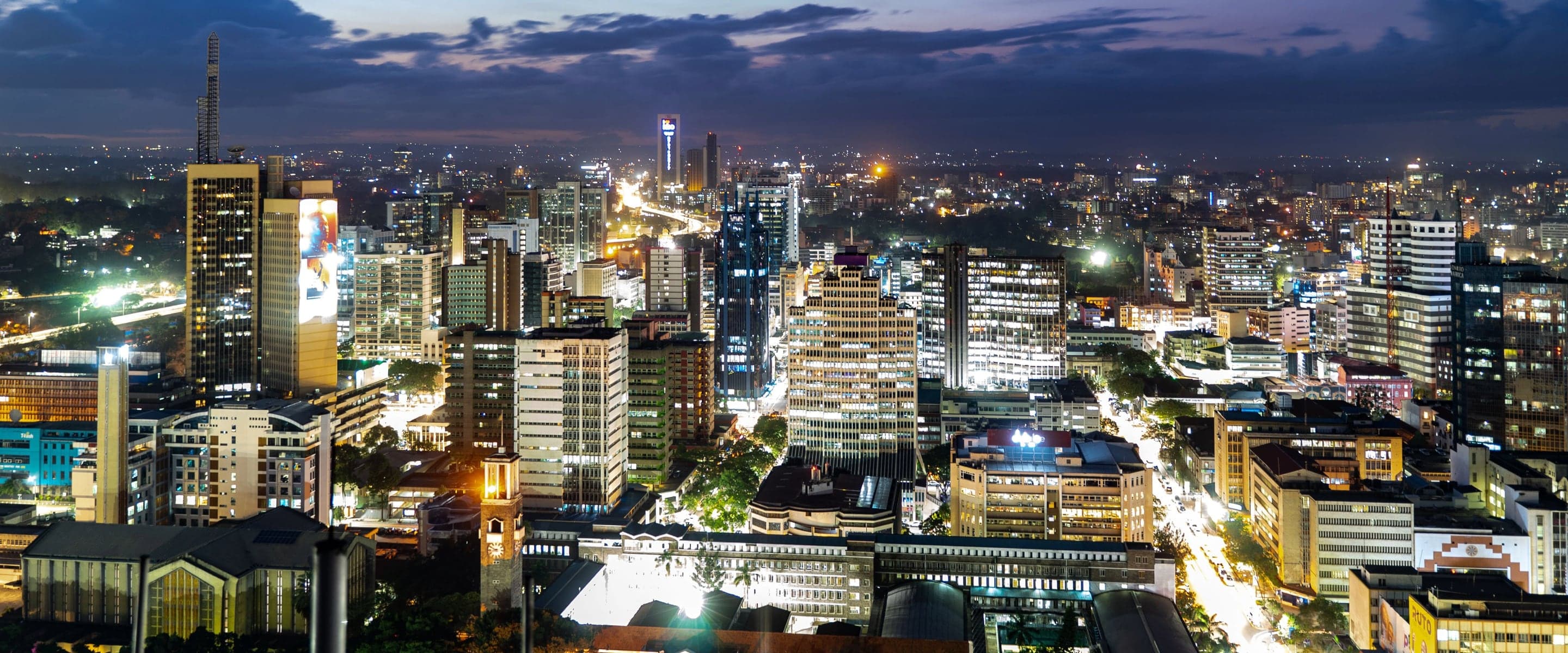 The Nairobi central business district at night, office towers lit across the skyline.